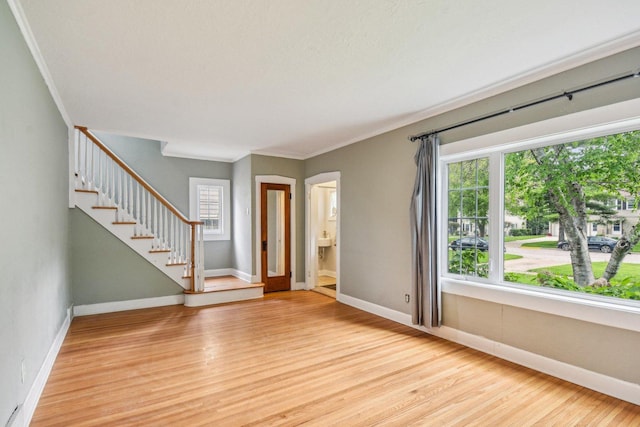 foyer entrance with light wood-style floors, stairs, baseboards, and ornamental molding