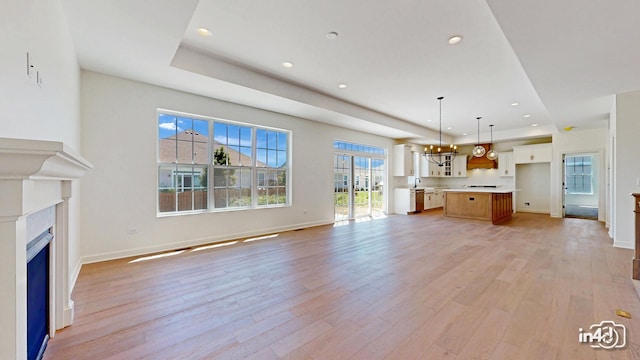 unfurnished living room with recessed lighting, a fireplace, light wood-style flooring, and baseboards