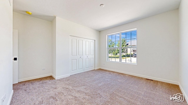 unfurnished bedroom with a closet, carpet flooring, visible vents, and baseboards