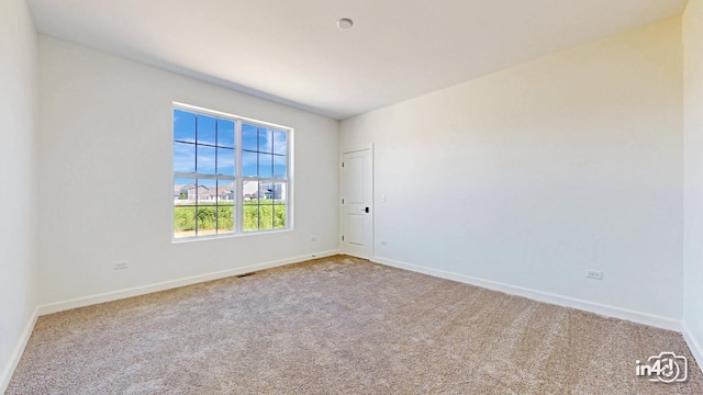 spare room with carpet, visible vents, and baseboards