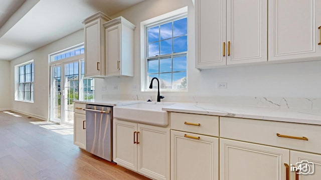 kitchen with a healthy amount of sunlight, dishwasher, light wood-style flooring, and a sink