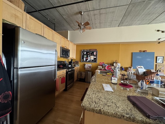 kitchen featuring stainless steel appliances, a sink, a ceiling fan, dark wood-style floors, and light brown cabinetry