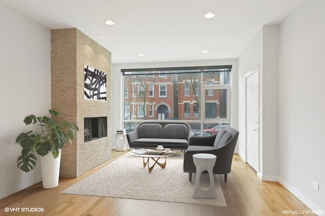 living area with baseboards, a fireplace, wood finished floors, and recessed lighting