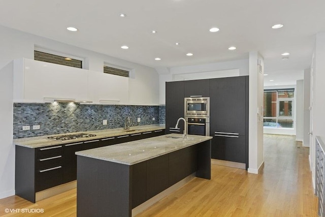 kitchen featuring stainless steel appliances, dark cabinetry, a sink, and modern cabinets