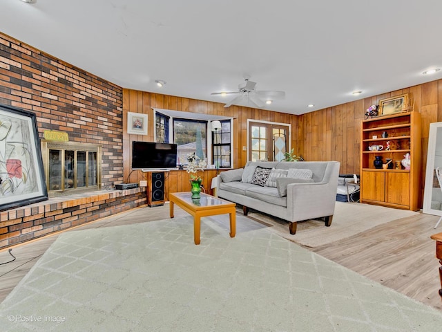 living area with wooden walls, a ceiling fan, wood finished floors, a fireplace, and recessed lighting