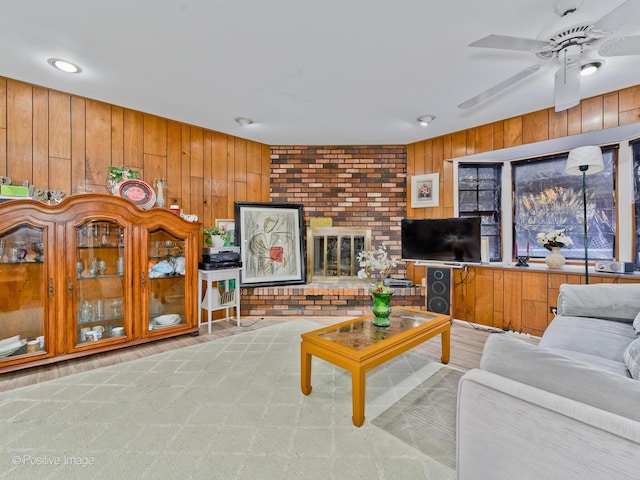 living area with ceiling fan, a brick fireplace, wood finished floors, and wooden walls