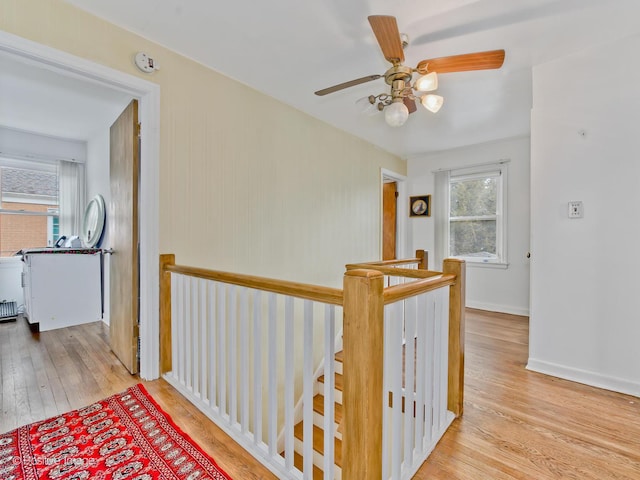 hallway featuring wood finished floors, an upstairs landing, and baseboards