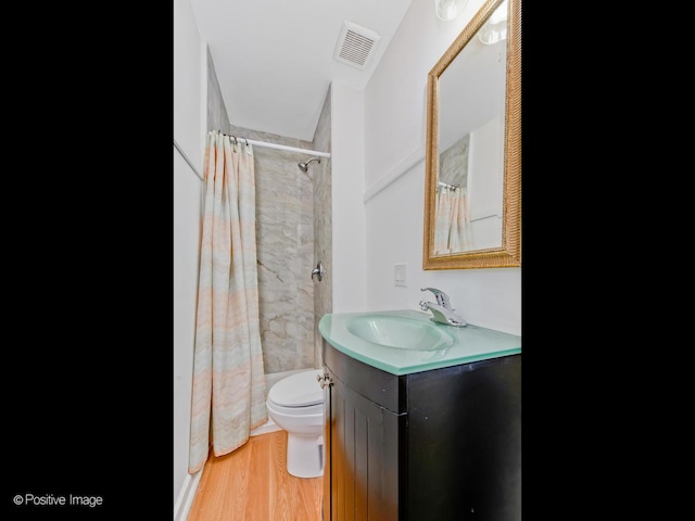 bathroom featuring curtained shower, visible vents, toilet, vanity, and wood finished floors