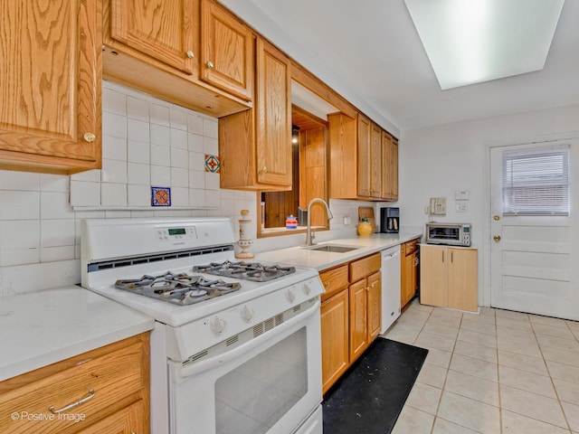 kitchen featuring white appliances, light tile patterned floors, a sink, light countertops, and backsplash