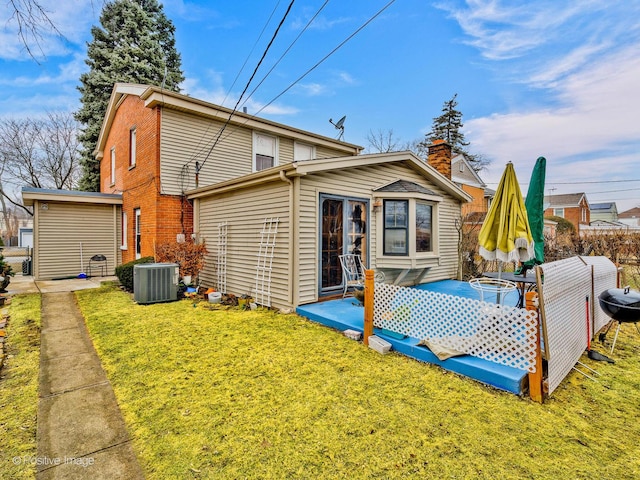 back of property featuring central AC unit, brick siding, a lawn, a chimney, and a patio area