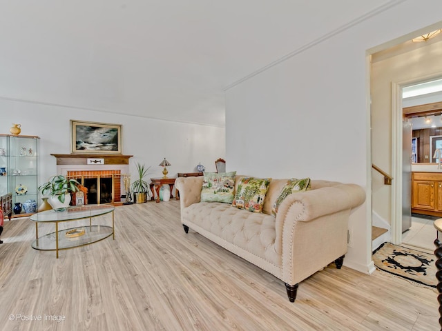 living room featuring light wood-style floors, stairs, and a fireplace