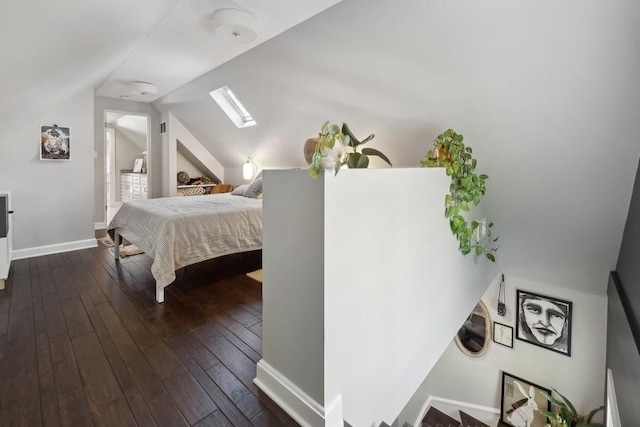 bedroom with vaulted ceiling with skylight, dark wood-style flooring, and baseboards