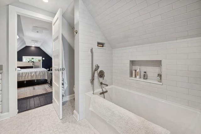 ensuite bathroom featuring toilet, ensuite bathroom, tile patterned flooring, vaulted ceiling, and a bath