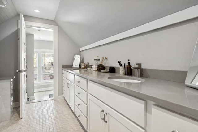 bathroom featuring vaulted ceiling, double vanity, a sink, and tile patterned floors