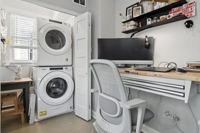 laundry room featuring light wood-style floors, laundry area, visible vents, and stacked washing maching and dryer