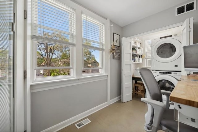 home office featuring stacked washing maching and dryer, baseboards, and visible vents