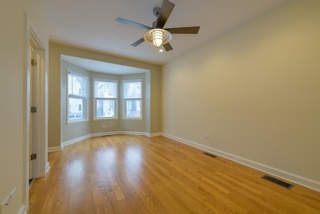 unfurnished room with light wood finished floors, visible vents, and baseboards