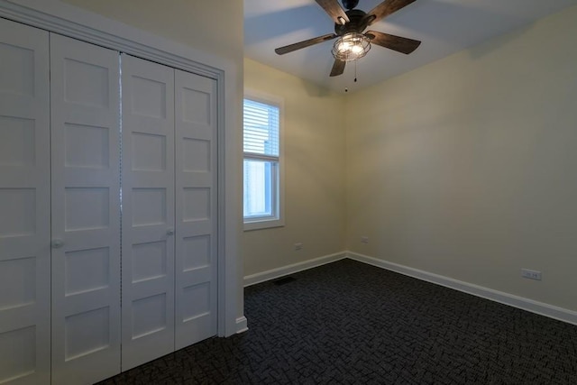 unfurnished bedroom featuring a closet, visible vents, dark carpet, a ceiling fan, and baseboards