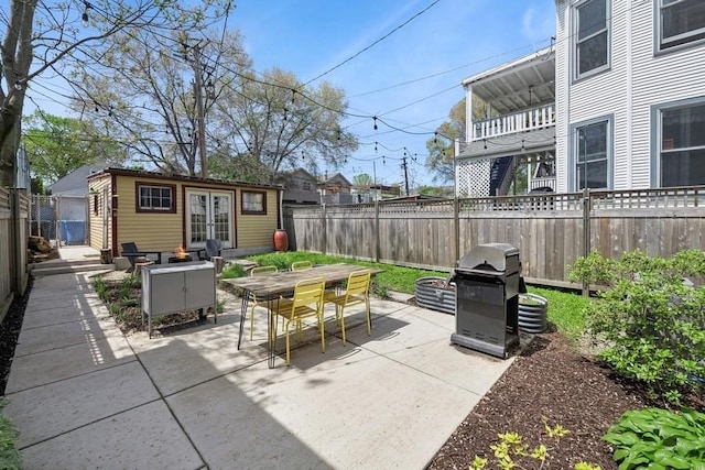 view of patio with french doors, area for grilling, a fenced backyard, an outdoor structure, and outdoor dining space