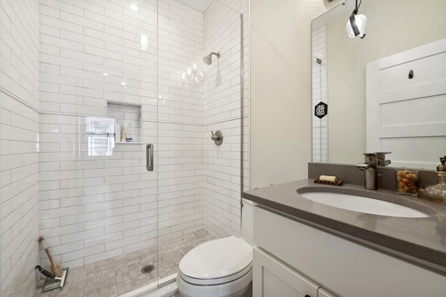 bathroom with toilet, a stall shower, and vanity