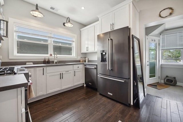 kitchen with visible vents, dark wood finished floors, stainless steel appliances, white cabinetry, and a sink