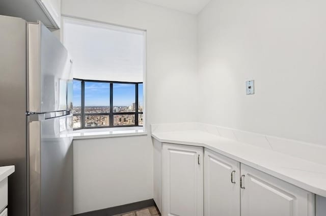 kitchen with light countertops, freestanding refrigerator, and white cabinets