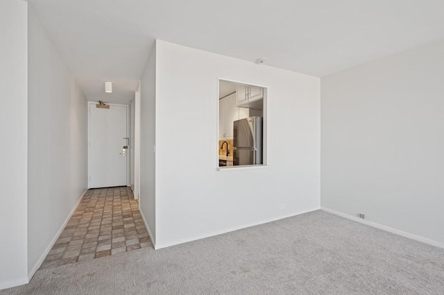 carpeted spare room with baseboards and a sink