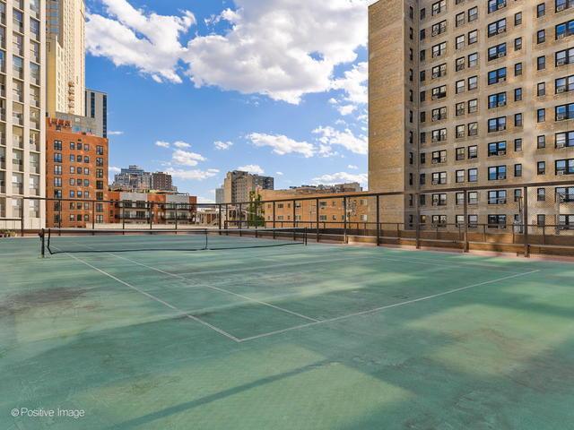 view of tennis court featuring a view of city and fence