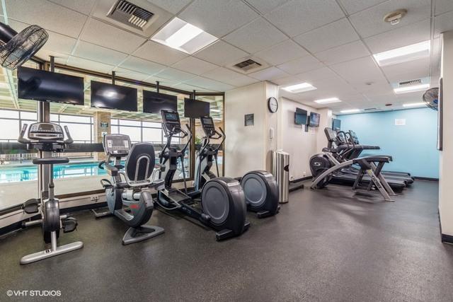 workout area with a drop ceiling, visible vents, and baseboards