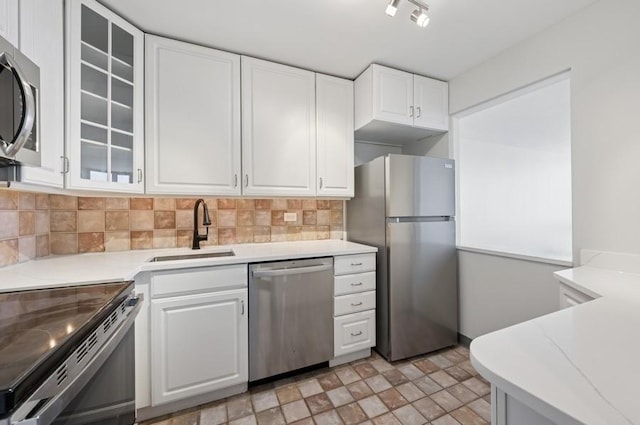 kitchen featuring light countertops, backsplash, appliances with stainless steel finishes, white cabinets, and a sink