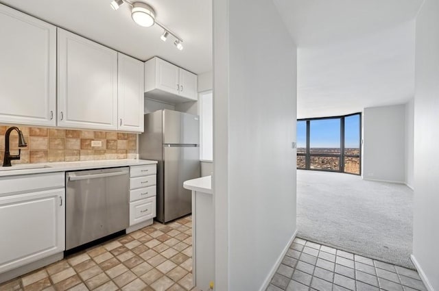 kitchen with tasteful backsplash, light countertops, light colored carpet, appliances with stainless steel finishes, and a sink