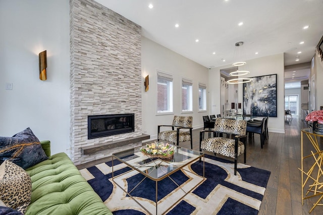 living room featuring recessed lighting, a stone fireplace, baseboards, and hardwood / wood-style flooring