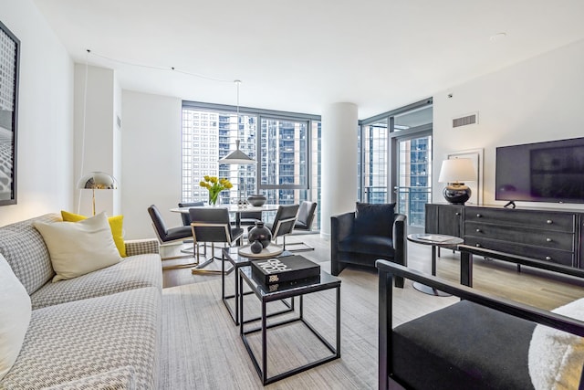 living room with a wealth of natural light, a wall of windows, and visible vents