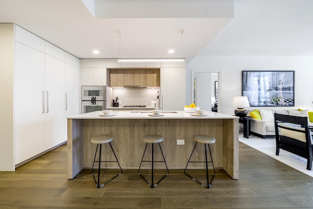 kitchen featuring modern cabinets, a breakfast bar, and dark wood-type flooring