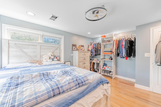 bedroom with recessed lighting, visible vents, baseboards, light wood-type flooring, and a walk in closet