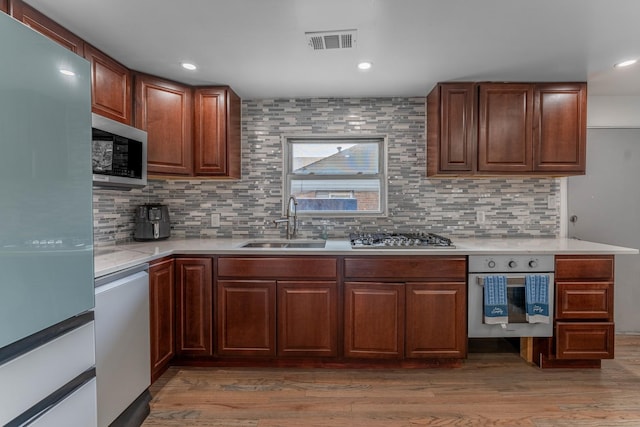 kitchen featuring a sink, visible vents, light countertops, appliances with stainless steel finishes, and light wood finished floors