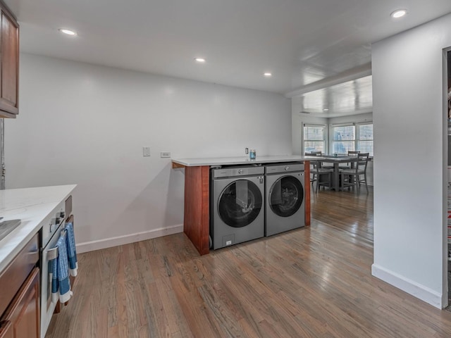 laundry room featuring laundry area, baseboards, wood finished floors, and independent washer and dryer