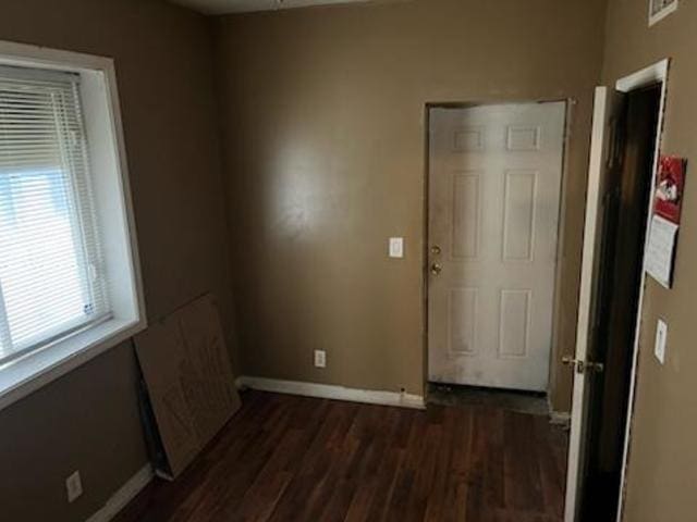 unfurnished bedroom featuring dark wood-style flooring, visible vents, and baseboards