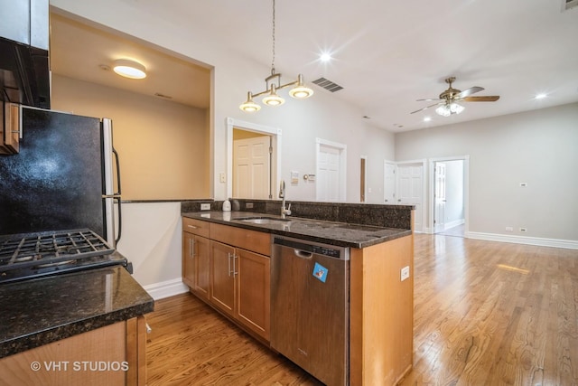 kitchen featuring visible vents, dark stone counters, ceiling fan, stainless steel appliances, and light wood-style floors