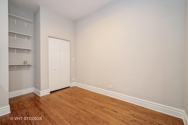 unfurnished bedroom with a closet, baseboards, and light wood-style floors