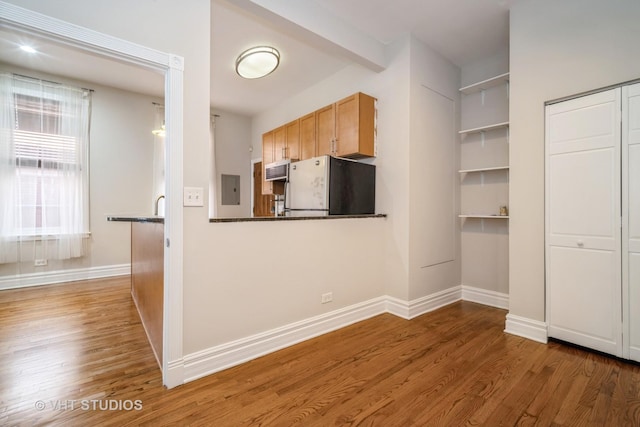 kitchen with electric panel, freestanding refrigerator, baseboards, and wood finished floors