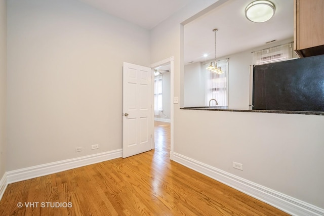 unfurnished room with baseboards, a notable chandelier, and wood finished floors