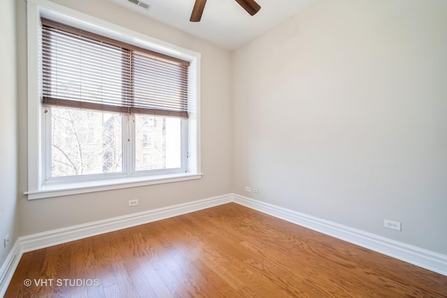 empty room featuring wood finished floors, a ceiling fan, baseboards, and visible vents