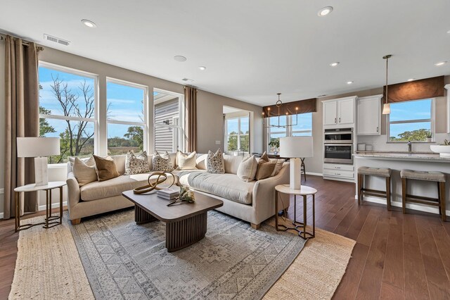 living room featuring dark wood-style floors, recessed lighting, visible vents, and plenty of natural light