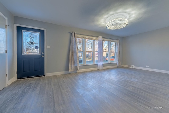 foyer with baseboards, visible vents, and wood finished floors