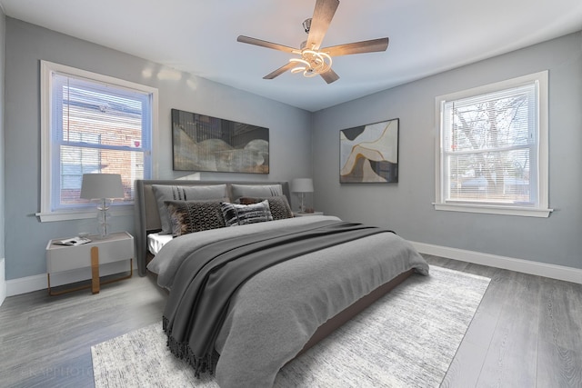 bedroom with a ceiling fan, baseboards, and wood finished floors