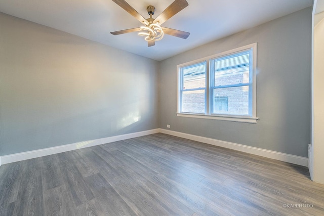 unfurnished room featuring dark wood-style floors, ceiling fan, and baseboards