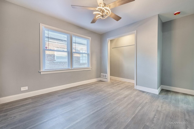 unfurnished bedroom featuring baseboards, visible vents, ceiling fan, wood finished floors, and a closet