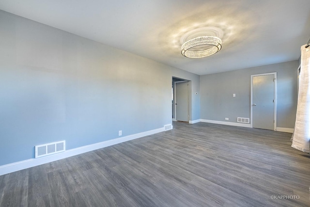 spare room featuring baseboards, visible vents, and dark wood-type flooring