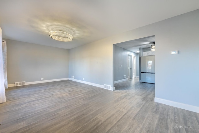 spare room with baseboards, visible vents, and wood finished floors